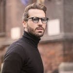 A fashionable man with glasses and a beard captured outdoors in Budapest.