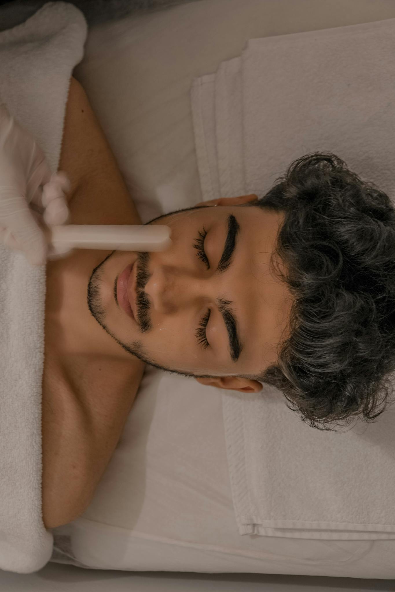 Adult man with closed eyes relaxing during a facial treatment in a spa setting.